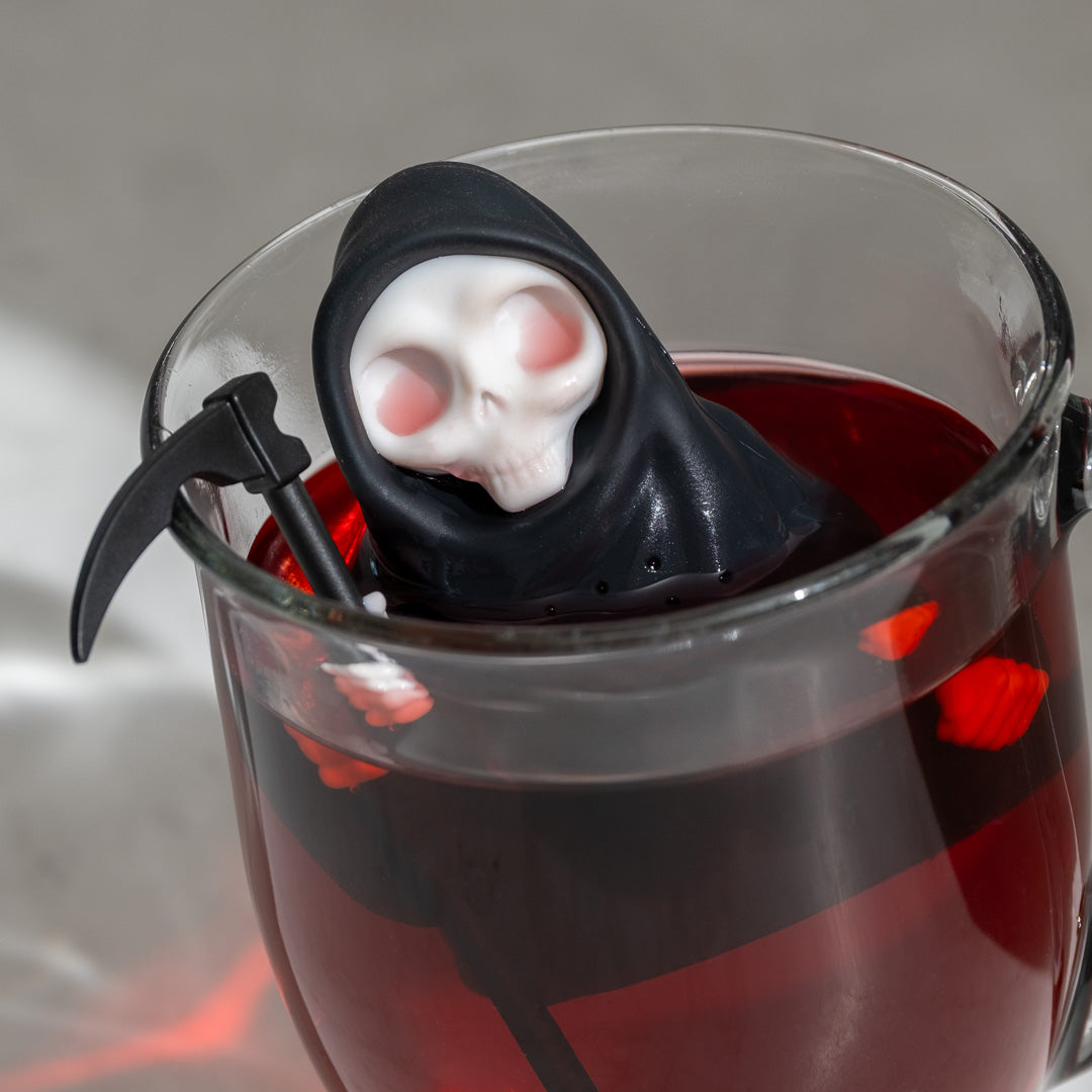 Grim steep tea infuser in a glass of red tea.